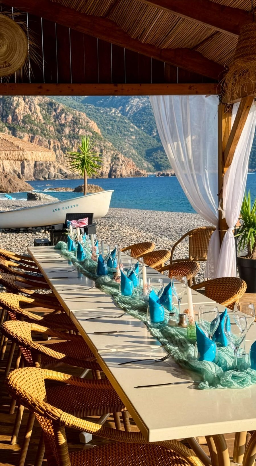 La grande tablée dressée sous la paillote, la plage derrière